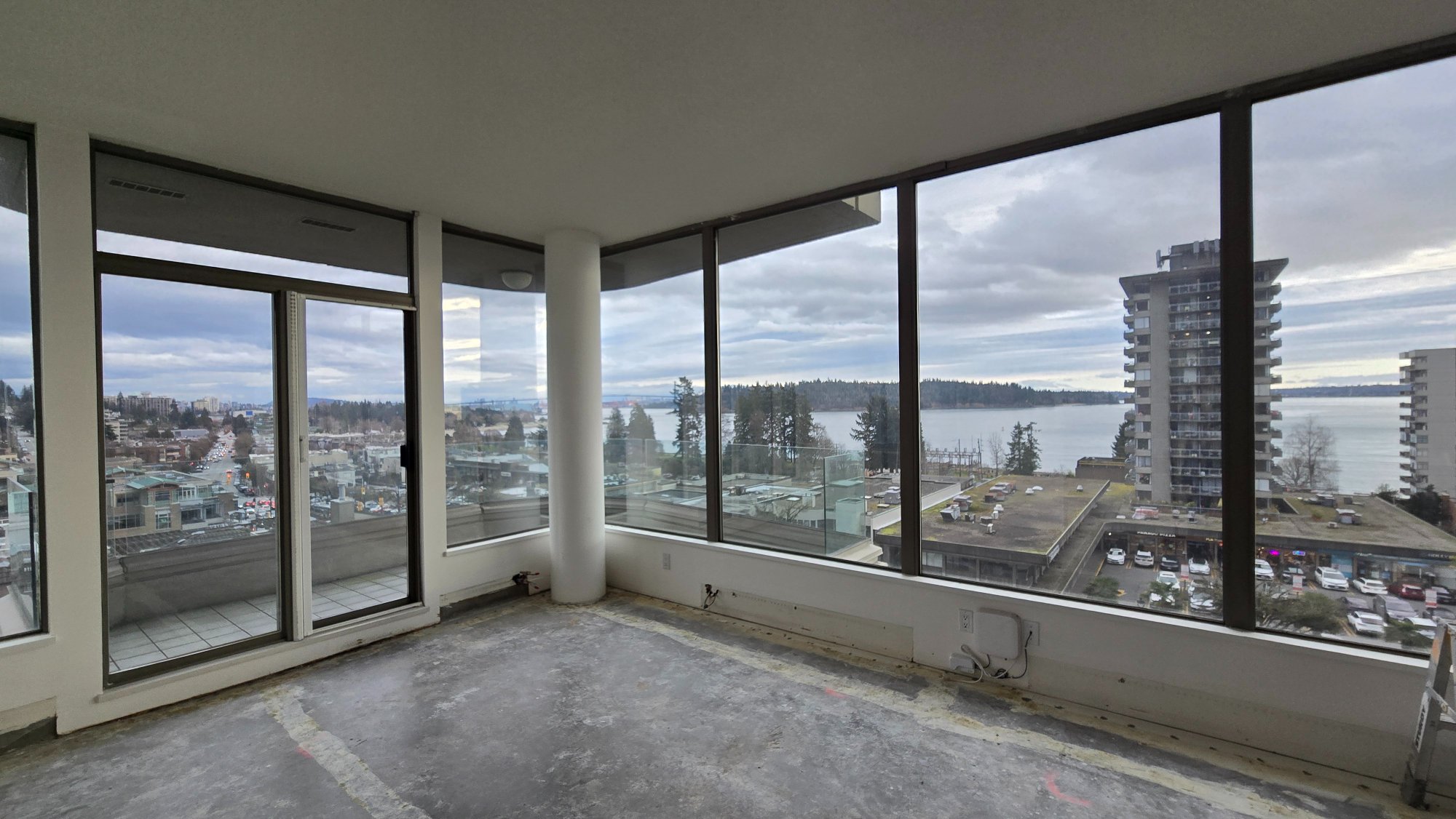 Condo living room after demolition — clean concrete subfloor with panoramic ocean and city views