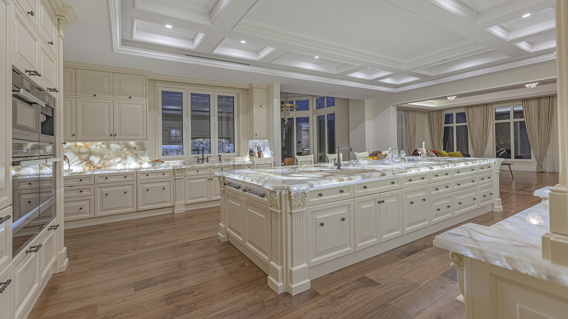 Altamont's Muse kitchen evening view with illuminated backsplash in West Vancouver