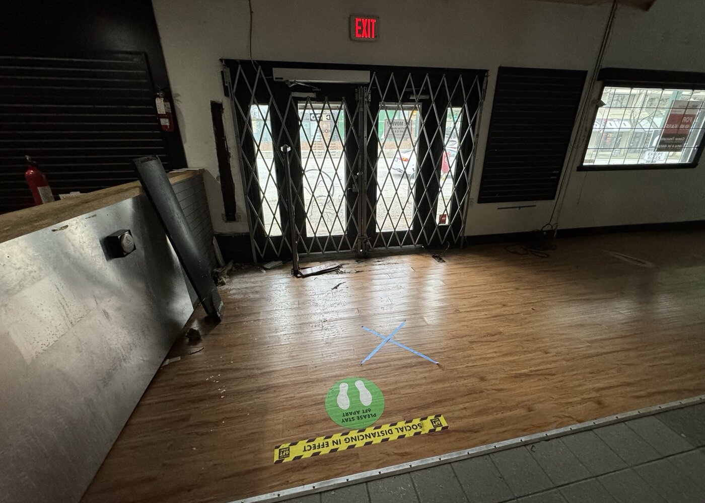 Entrance area with existing flooring and security gate during assessment phase of retail restoration
