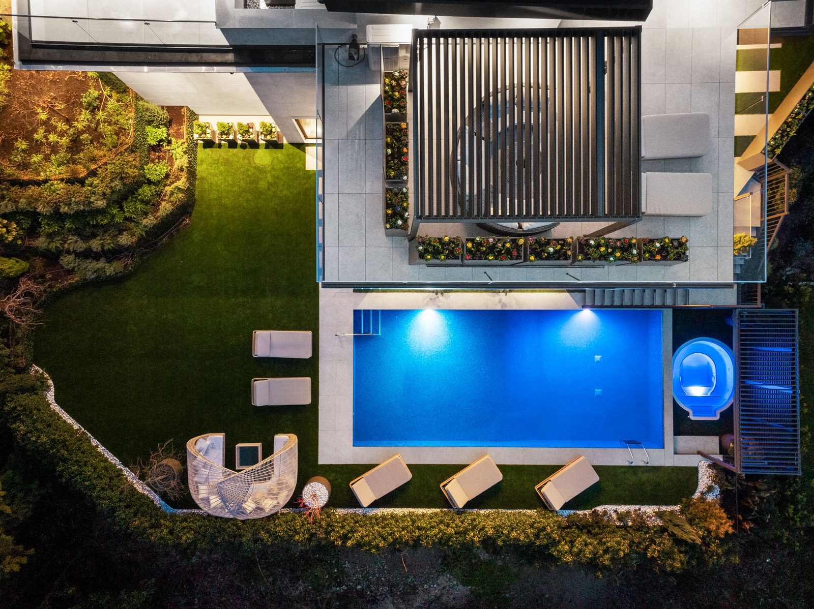 Front facade of concrete and steel luxury home with illuminated interiors and butterfly roof West Vancouver