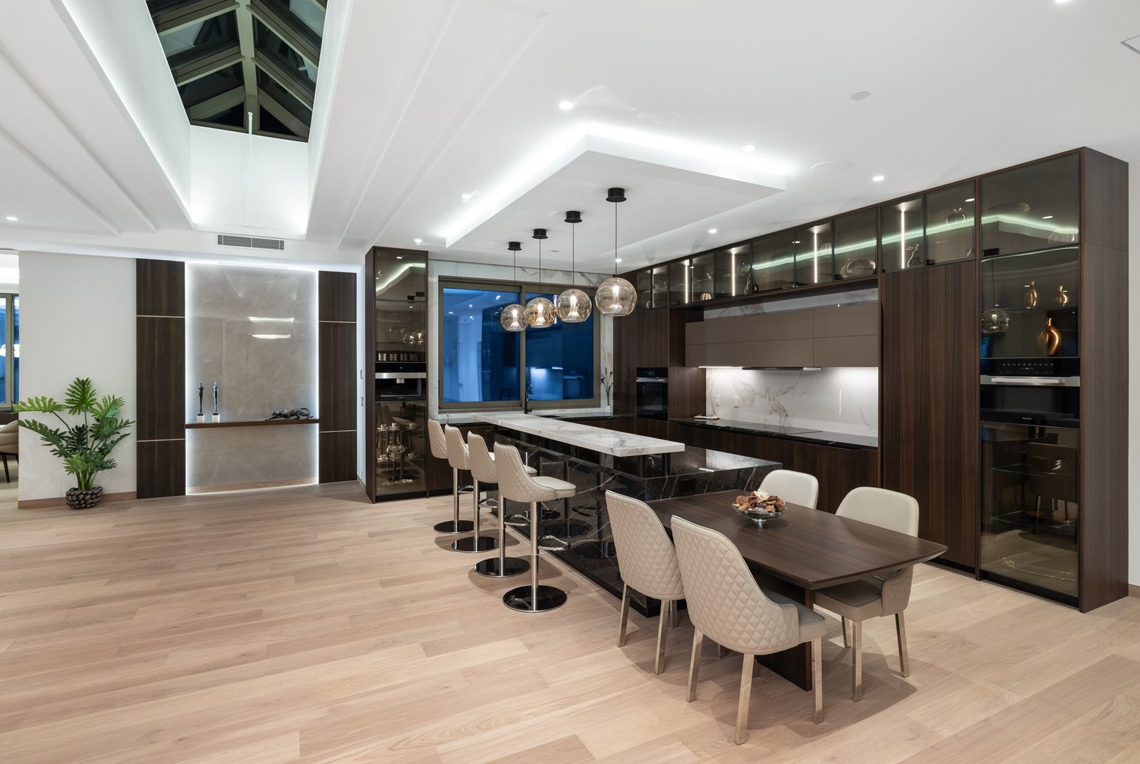 Kitchen and dining area with glass-front LED display cabinets and quilted dining chairs luxury West Vancouver home