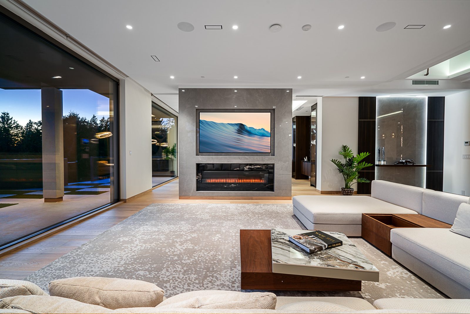 Living room with linear fireplace wall-mounted TV white sectional and sliding glass to pool terrace West Vancouver