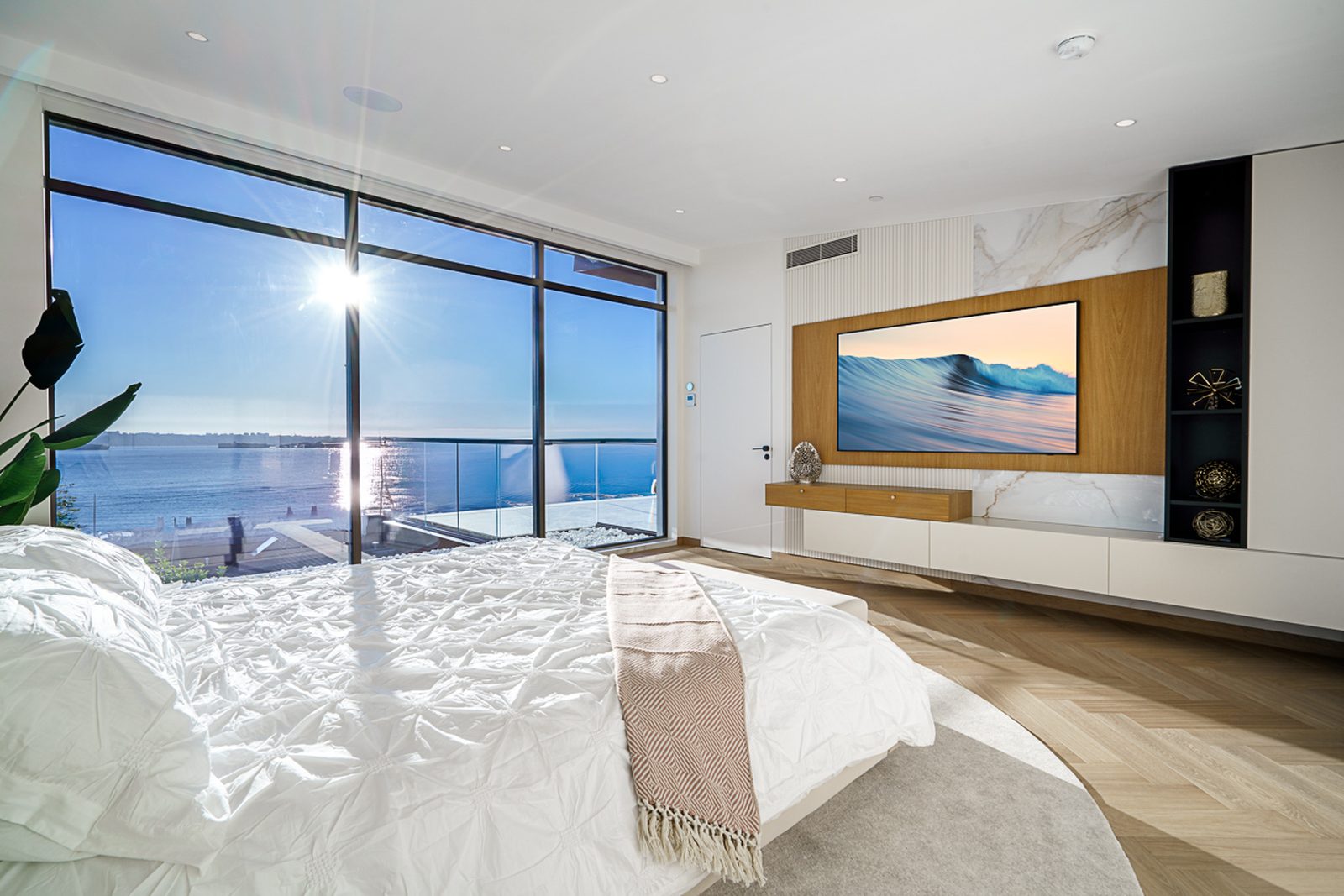 Master bedroom in morning light with panoramic ocean view marble wall and walnut media console The Butterfly