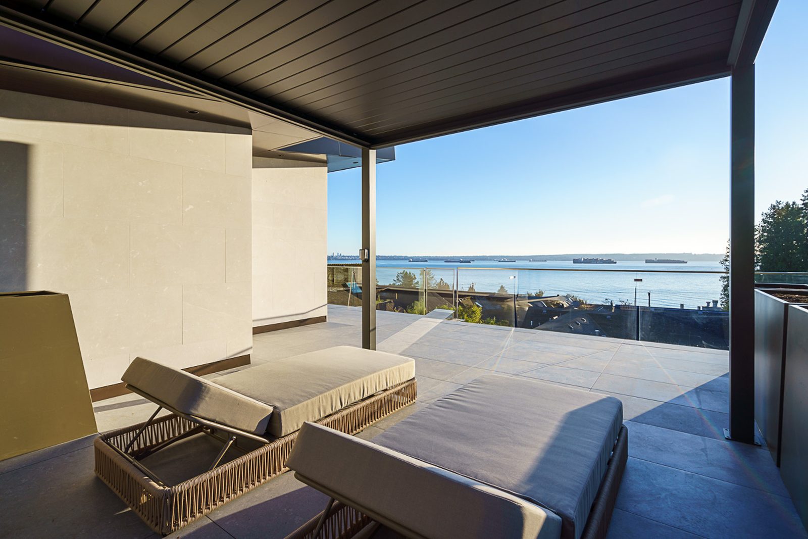 Covered upper terrace with loungers and panoramic ocean sunset view at The Butterfly West Vancouver