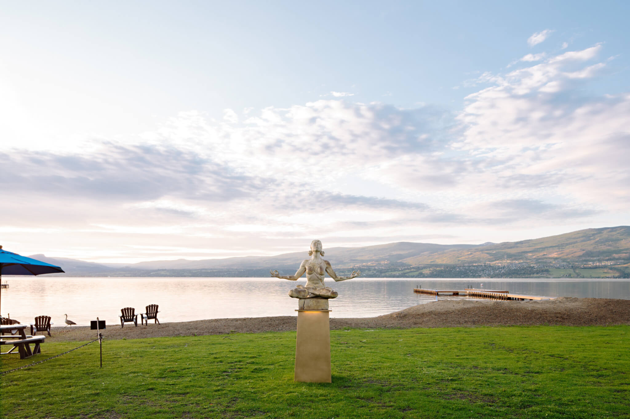 Frind Estate Winery lakefront grounds — sculpture, Okanagan Lake beach, dock, and mountain views at the former Bennett Estate in West Kelowna