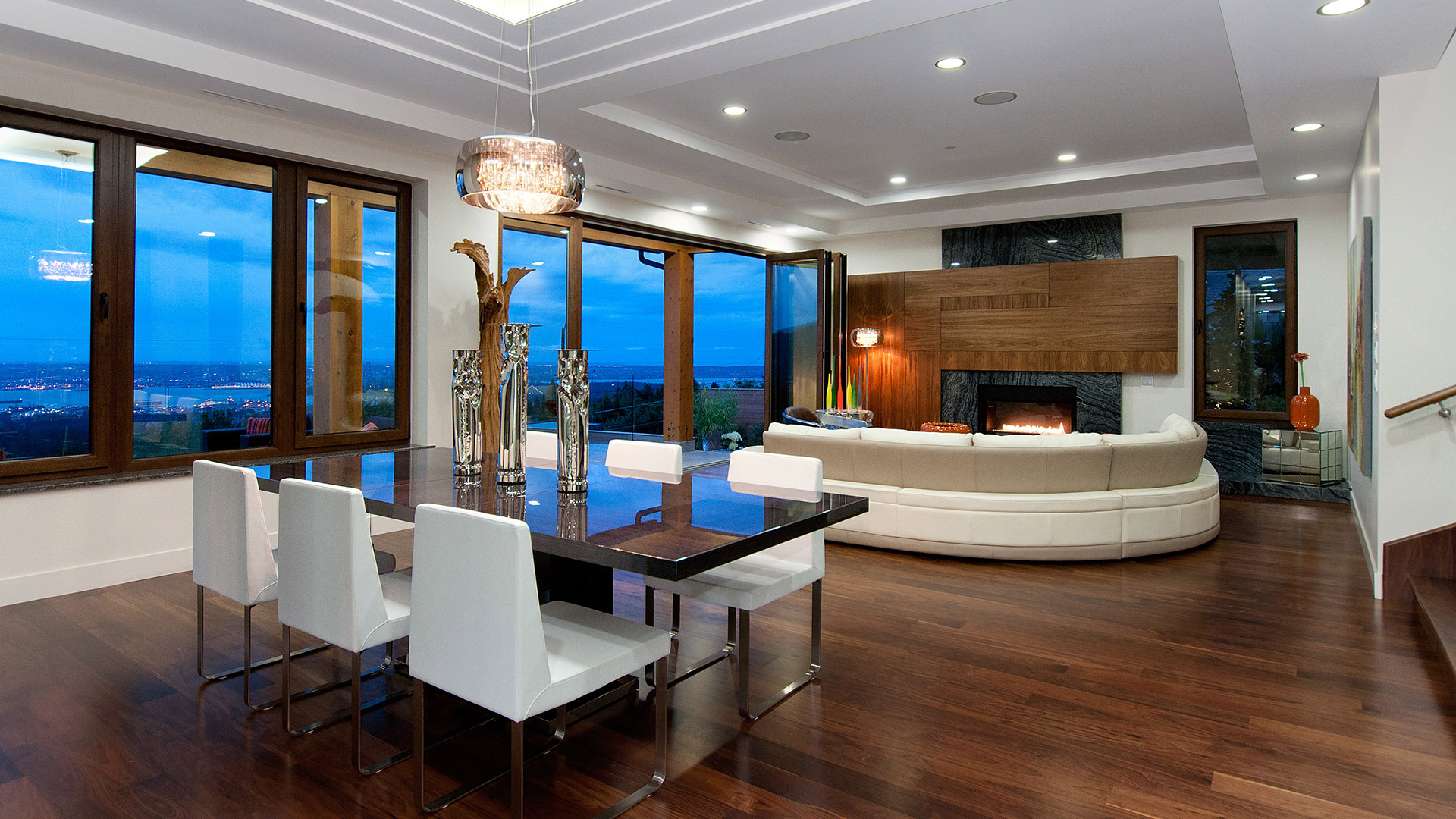 Open-plan living and dining room with walnut flooring curved white sectional marble and walnut fireplace surround coffered ceiling and panoramic city views Millstream British Properties West Vancouver