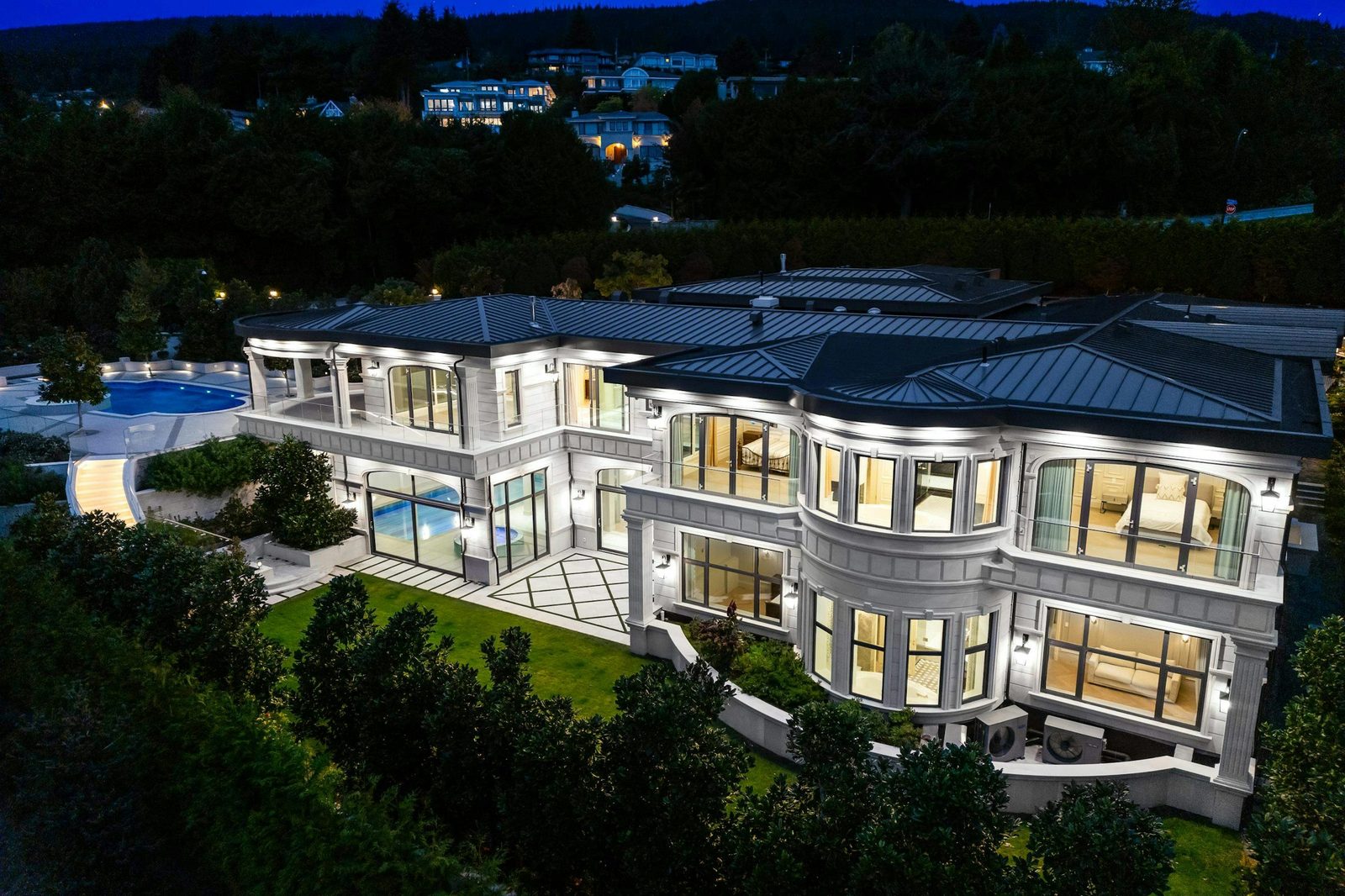 Aerial night view of Montbeau Eyremount luxury estate showing pool and roofline in West Vancouver