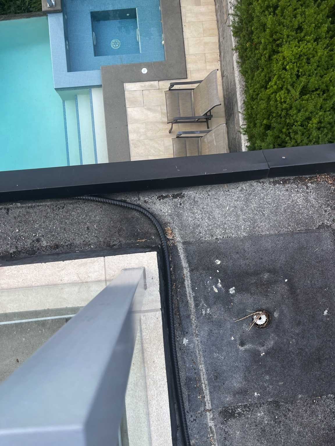 Existing deck torch-on membrane with drain penetration at Newdale Court overlooking pool deck before electrically heated snow melter and new tile installation