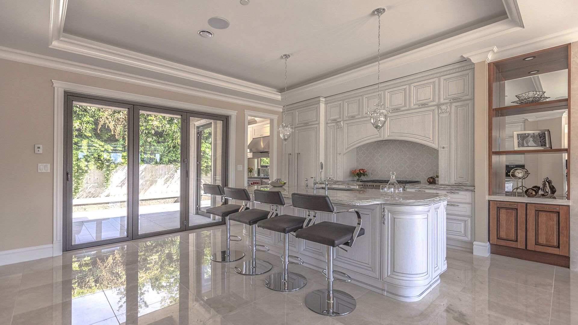 Classical Italian solid wood kitchen cabinetry with arched range hood valance and marble countertops facing garden sliding doors in West Vancouver home by Eurohouse Construction