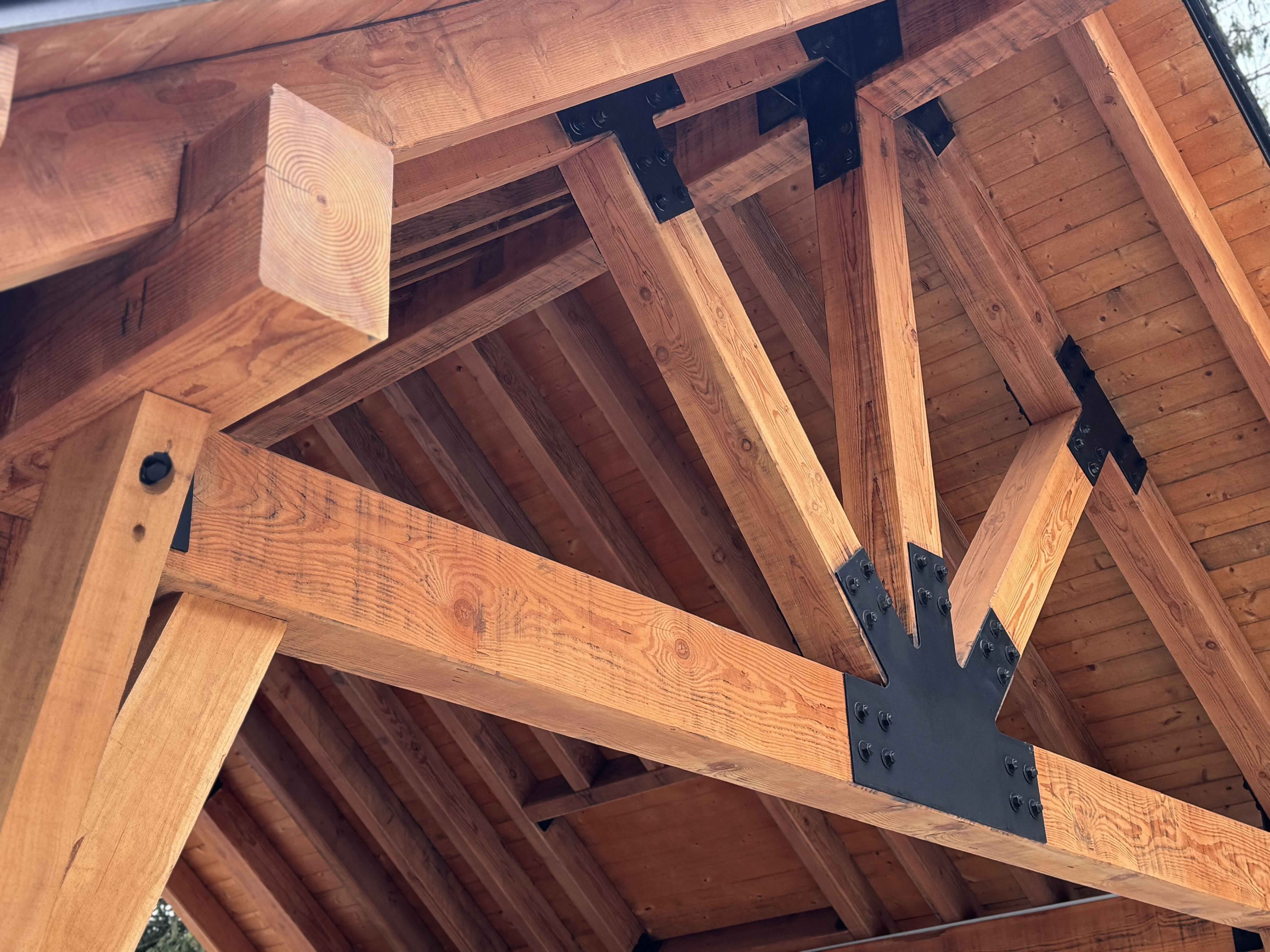 Cedar post-and-beam gazebo with exposed timber trusses and stone patio at Rainbow in Whistler by Eurohouse Construction