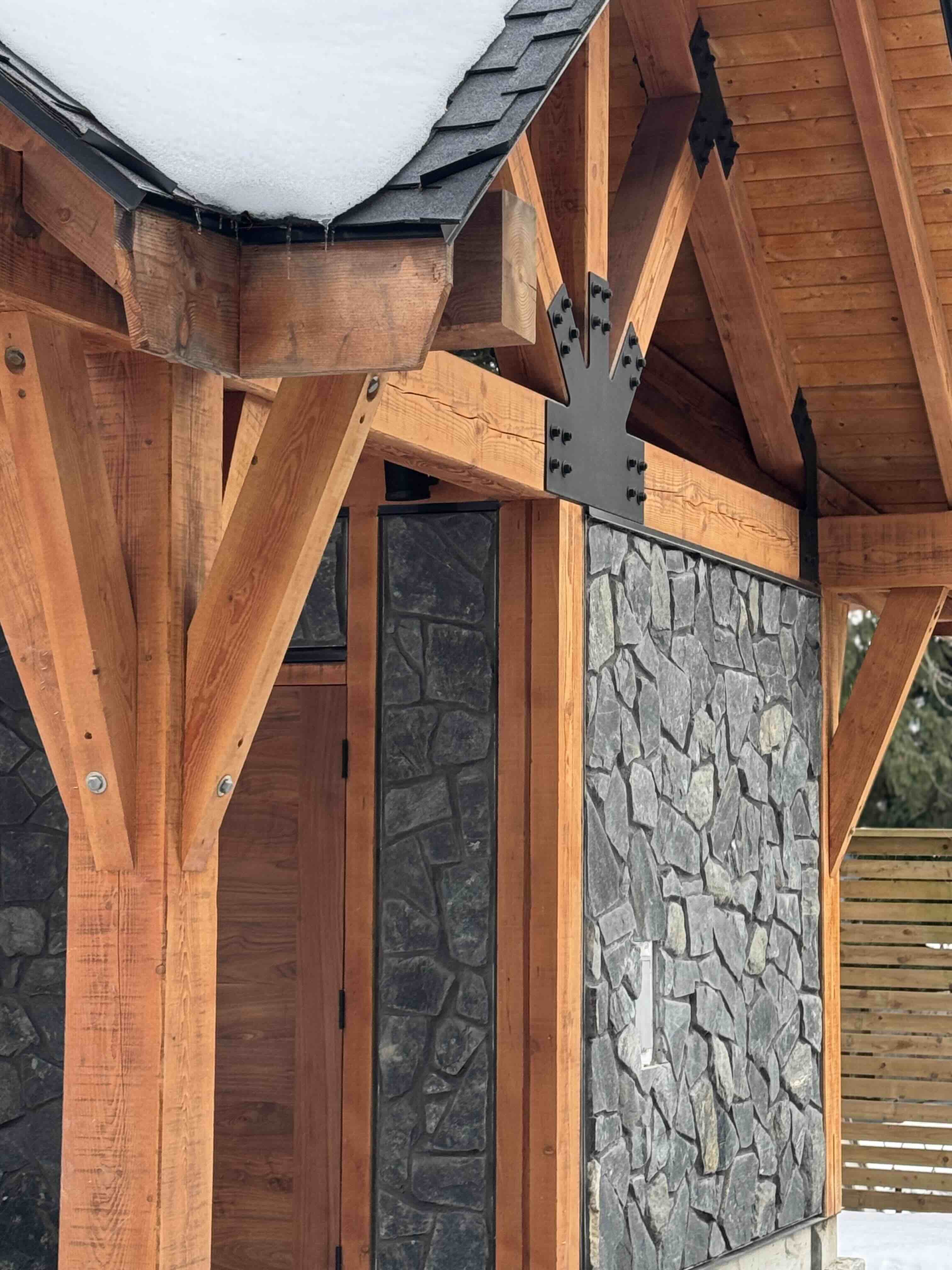 Interior view of timber gazebo showing stone wall, cedar posts, and covered hot tub area at Rainbow in Whistler by Eurohouse Construction