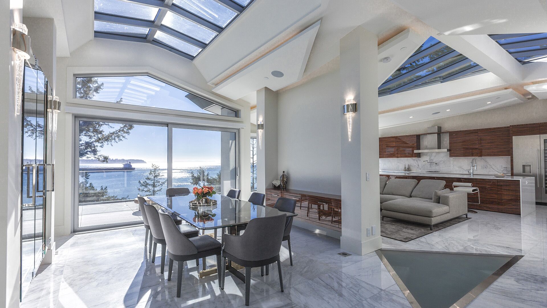 Open plan dining and living area with dramatic vaulted skylights ocean views glass dining table and zebrawood living room at The Riva Club designed and installed by Eurohouse Construction