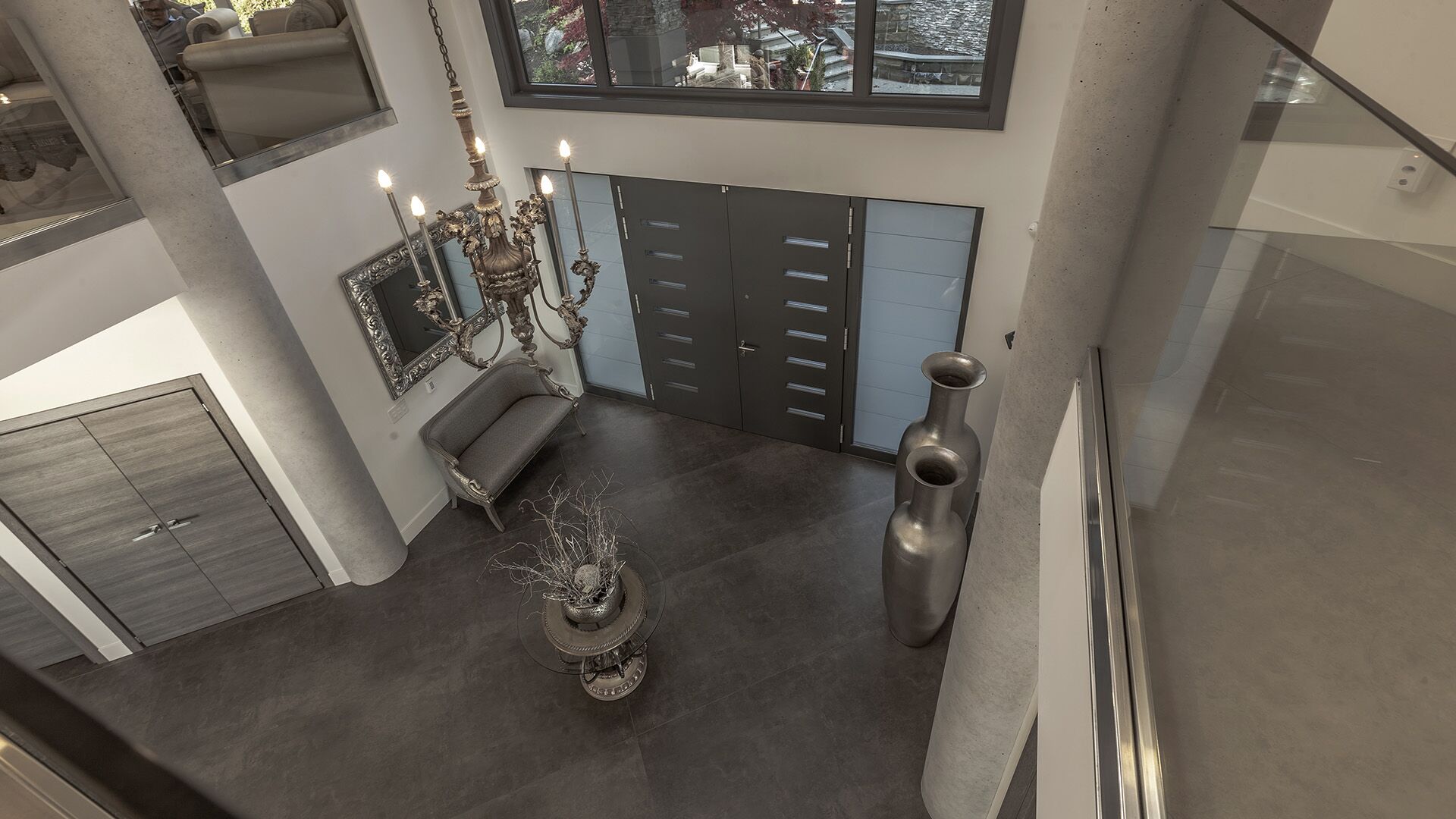 Overhead view of double-height foyer showing massive 1.2 by 3.6 metre porcelain floor tiles glass staircase railing and Italian entry door at The Zen on Bramwell renovated by Eurohouse Construction