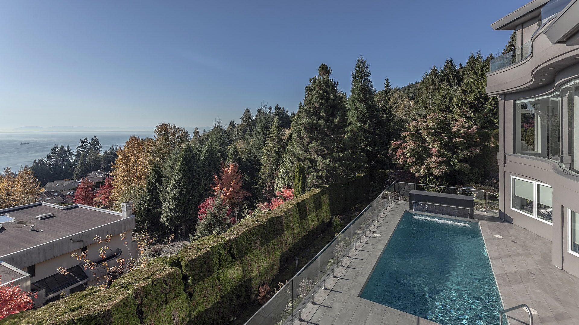Infinity pool with porcelain tile deck glass railing ocean and mountain views British Properties hillside setting exterior hard surface replacement at The Zen on Bramwell renovated by Eurohouse Construction