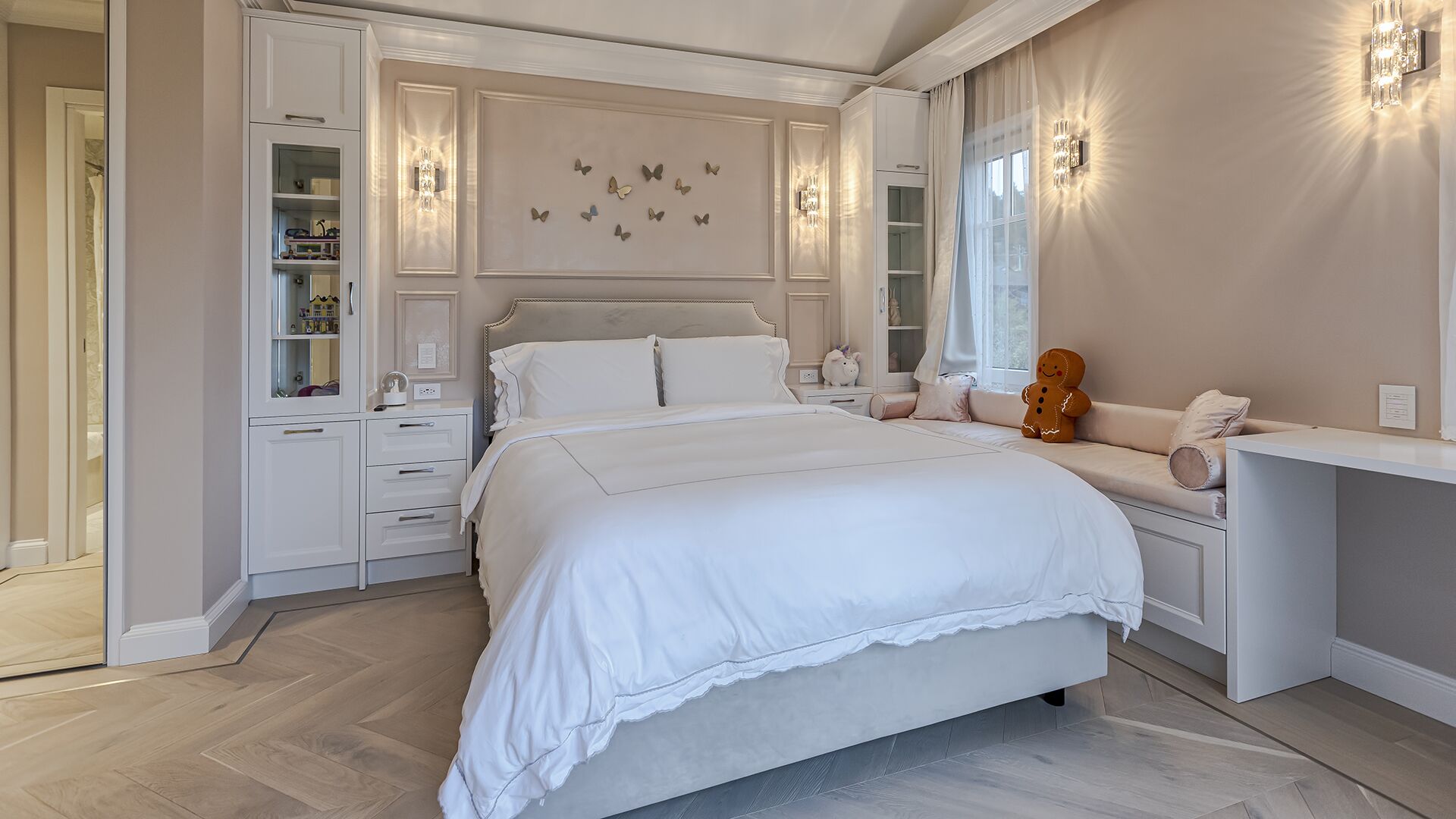 Elegant bedroom with butterfly wall art crystal sconces built-in storage and window seat luxury West Vancouver home by Eurohouse