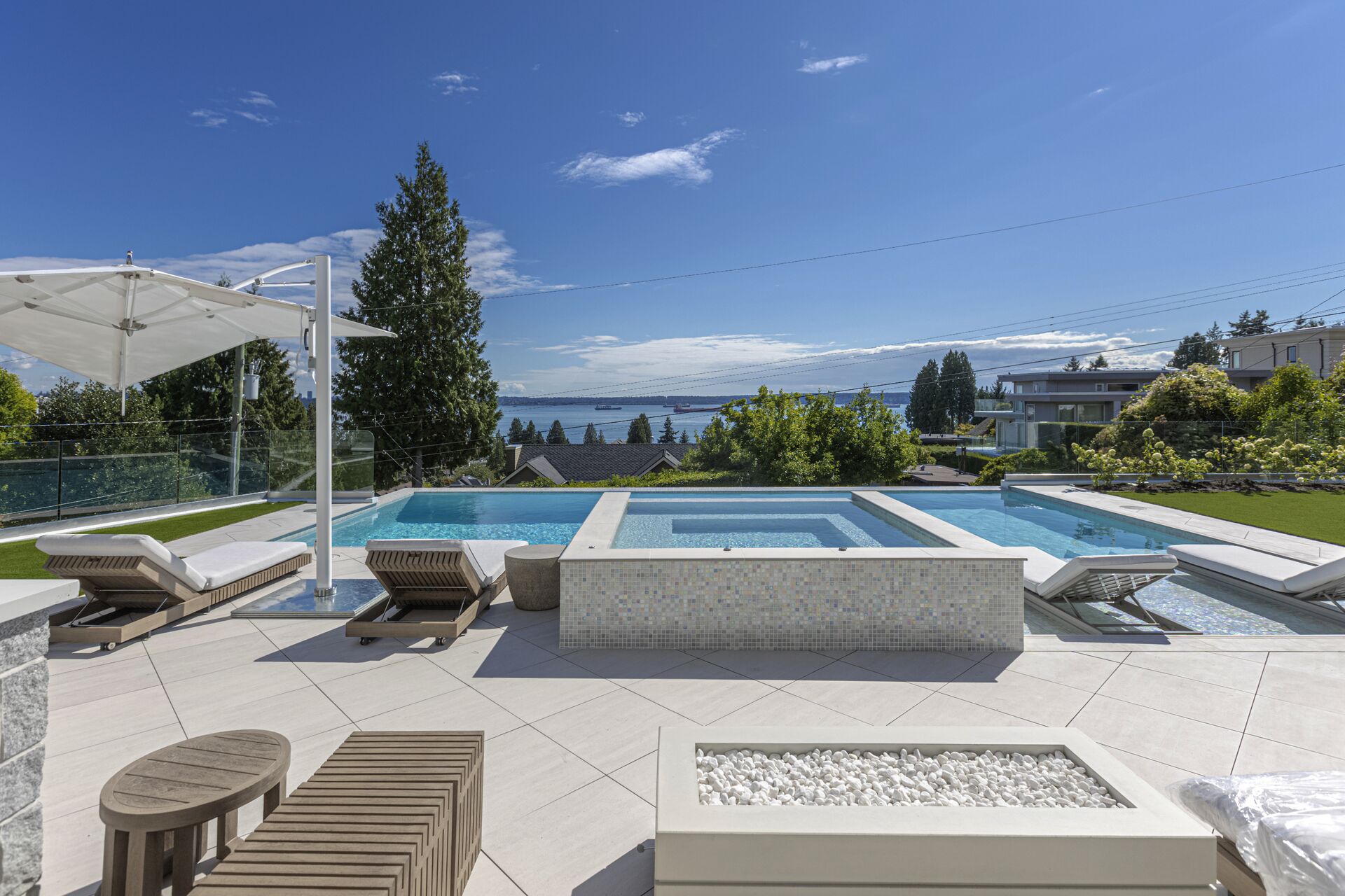 Resort-style pool with mosaic tile hot tub fire pit and ocean views at West Vancouver luxury estate Eurohouse Construction
